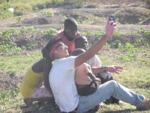 Haitians pose for a photo op on an iPhone. By Kelly Craig. 